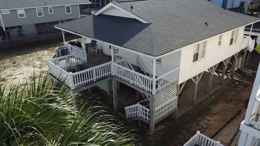 Raised home with white rail porches